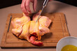Chef prepares a whole raw chicken in the kitchen. Man prepares raw chicken for barbeque, injecting cider into the meat.