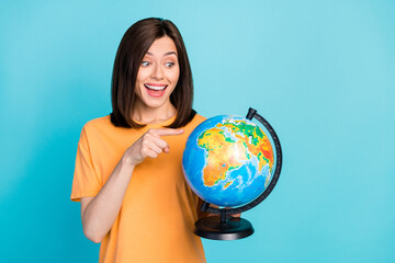 Canvas Print - Portrait of positive impressed astonished woman long hairstyle yellow t-shirt look directing at globe isolated on blue color background