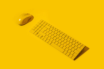 yellow wireless keyboard and yellow computer mouse on a yellow background