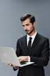 © SHOTPRIME STUDIO - Man business looks into laptop and works thoughtfully online via internet in business suit video call business talks on gray background copy place