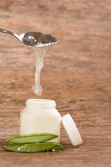 person placing Aloe Vera pulp in a plastic container with a metal spoon