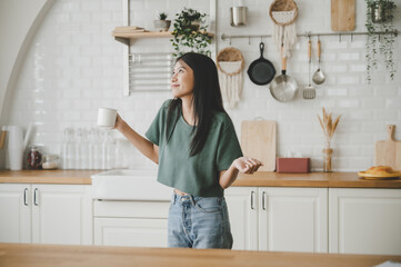 Poster - Asian young woman dancing in kitchen room. She happy and relaxing at free time on weekend