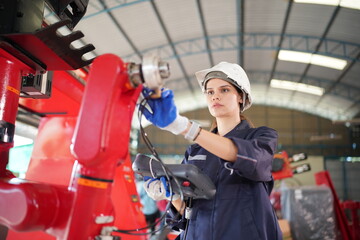 Robotics engineer working on maintenance of modern robotic arm in factory warehouse