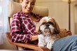 Cute dog relaxing on woman's lap and looking at camera.