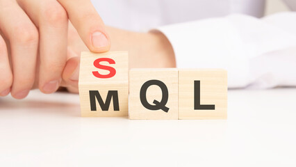 Wall Mural - SQL or MQL symbol. Businessman turns cubes and changes words 'MQL marketing qualified lead' to 'SQL sales qualified lead'. Beautiful white background.