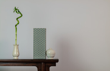 Bamboo, Chinese antique ceramics and traditional style book on wooden table against white wall