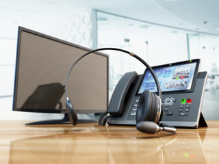 Modern VoIP phone and headset standing on wooden office table. Call center, marketing and technical support concept. 3D illustration