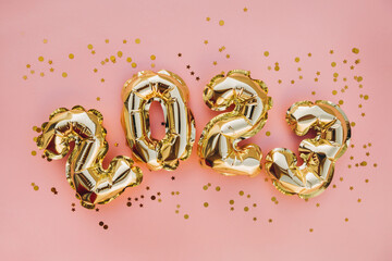 Happy New Year 2023 greeting card. 2023 golden foil balloons numbers and confetti. Top horizontal view copy space new year and christmas holiday concept.