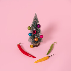 Wall Mural - Decorated Christmas tree and hot peppers on pastel pink background