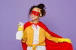 © ViDi Studio - Young housekeeper woman wear yellow shirt rubber gloves red super hero cloak mask hold detergent bottles tidy up clean house isolated on plain pastel light purple background studio. Housework concept.