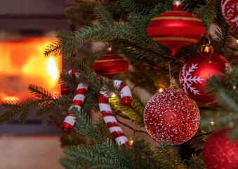 Wall Mural - Christmas tree decoration and lights close up view, burning fireplace background.