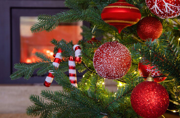 Wall Mural - Christmas tree decoration and lights close up view, burning fireplace background.