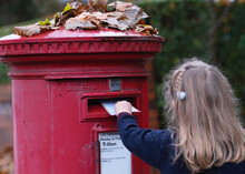 Cute Girl Is Posting A Letter For Santa Claus Into The Classic Red English Postbox. Popular Children Christmas Activity.
