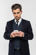 © LIGHTFIELD STUDIOS - successful businessman in suit messaging on smartphone isolated on grey