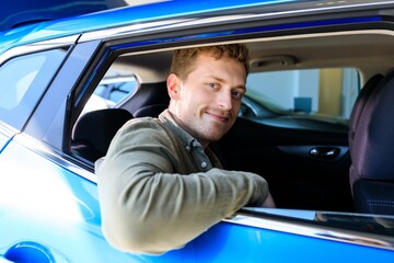 A man sits in a car and gets high from his purchase. A businessman bought a new car from a car dealership