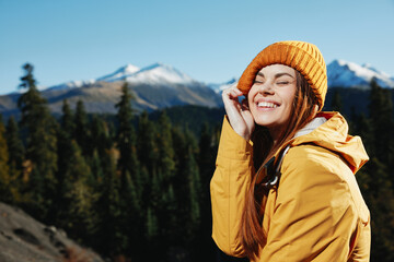 Woman smile with teeth hiker portrait in yellow raincoat travel in the fall and hiking in the mountains in the sunset sunshine freedom