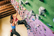 © ADDICTIVE STOCK - Sportswoman climbing wall with help of trainer