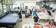 © guruXOX - In a large modern printing plant, operators work on various types of machines for printed material