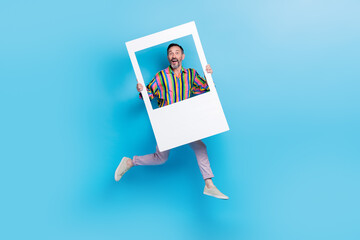 Wall Mural - Full length photo of bearded cheerful crazy funky man wear trendy striped clothes hold big photography isolated on blue color background