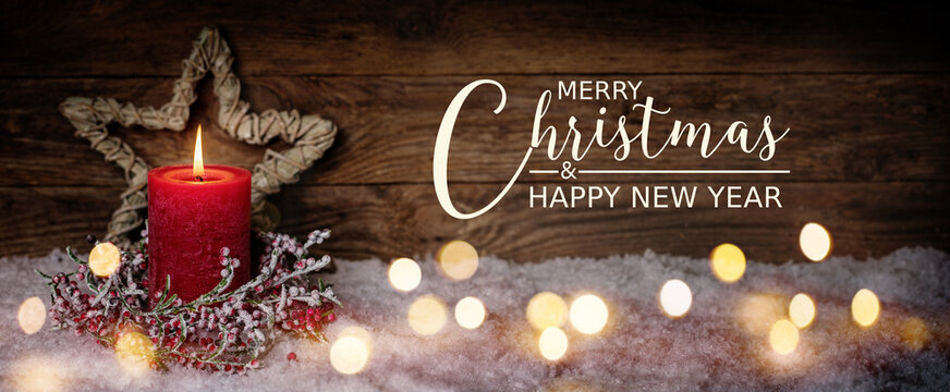 Fototapete - Christmas Greeting Card with English text Merry Christmas and Happy New Year. Panorama, Banner. Christmas candle in winter snow landscape with magic lights. Xmas Wood background with copy space.
