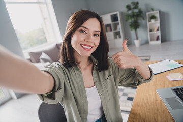 Portrait of positive attractive lady sitting chair take selfie hand finger demonstrate thumb up modern office indoors