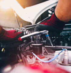 Auto mechanic repairing engine with socket wrench in the auto repair garage, automotive maintenance service concept