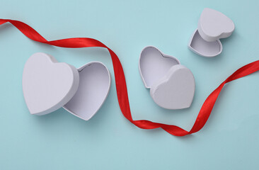 Wall Mural - Empty white boxes in the shape of a heart with red ribbon on blue background. Top view