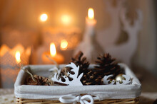 Basket With Pine Cones, Christmas Ornaments And Seasonal Spices. Soft Blanket, And Lit Candles In The Background. Selective Focus.