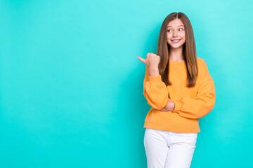 Sticker - Photo of small excited girl wear orange stylish sweater white pants finger point mockup new shopping center open isolated on cyan color background