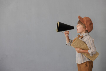 Newsboy shouting against grunge wall background. Boy selling newspaper