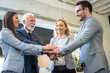© Bojan - Group of young and senior business people join hands together, celebrating their success in office.