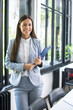 © Bojan - Young businesswoman holding clipboard in office.