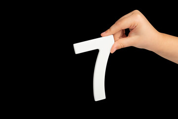Aufkleber - Number seven in hand isolated on black background. Number 7 in a child's hand on a black background. To be inserted into a project or design.