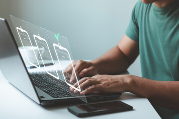 Man hand using a laptop computer with a virtual screen and document for online approval paperless quality assurance and ERP management concept.