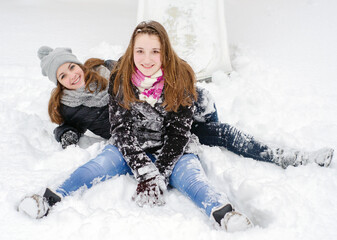 Two beautiful young teenage girls playing in the snow on a beautiful winter day