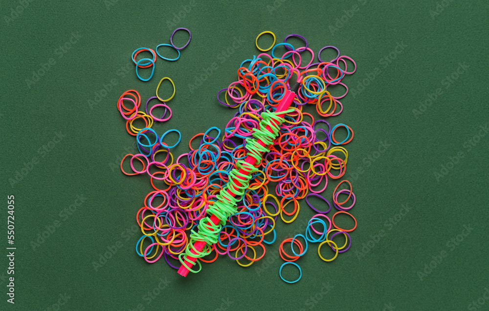 Pencil with colorful rubber bands on green background