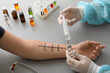 Doctor with syringe and ampule making allergy skin test to patient in clinic, closeup