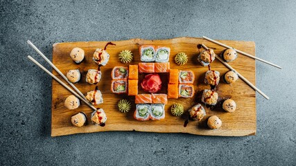 Wall Mural - Closeup of delicious sushi set on a wooden board on a gray table