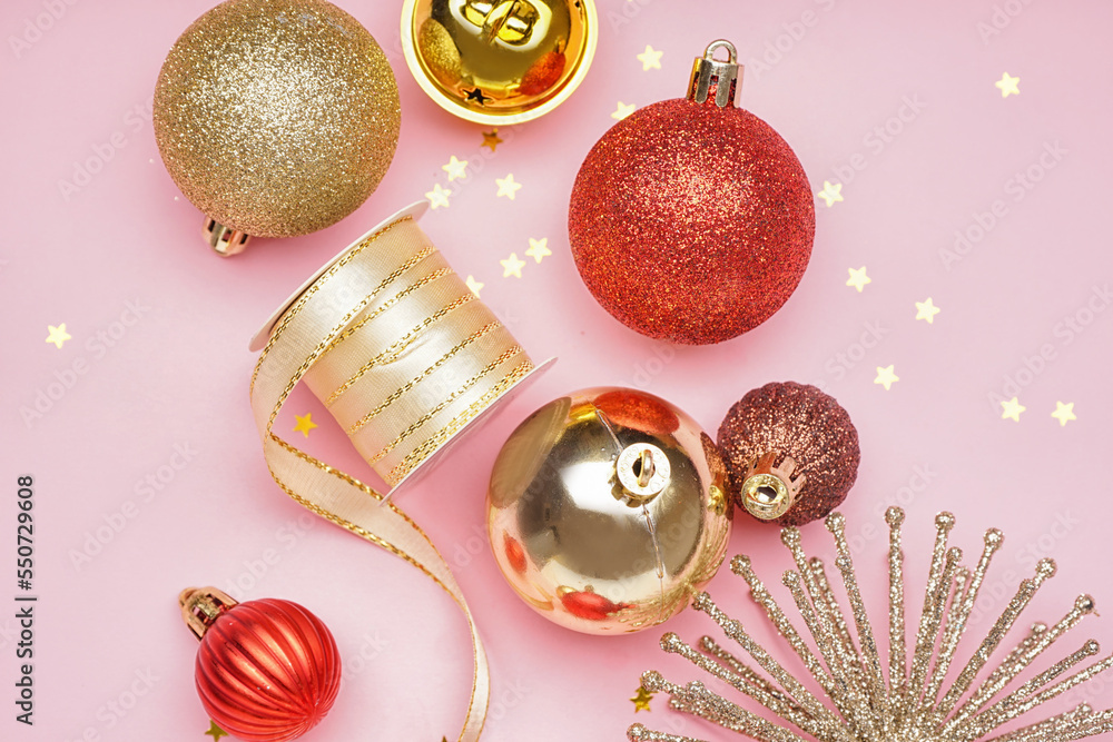 Shiny Christmas decorations with ribbon on pink background