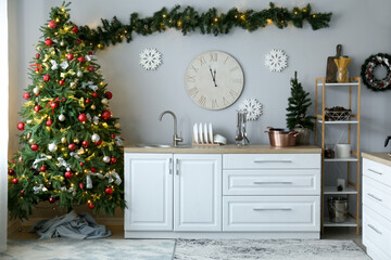 Interior of kitchen with Christmas trees, white counters and big clock