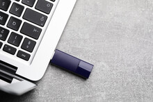 Modern Usb Flash Drive Attached Into Laptop On Light Grey Table, Flat Lay. Space For Text
