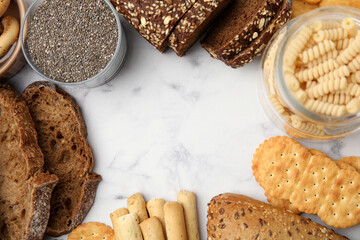 Frame made of different gluten free products on white marble table, flat lay. Space for text