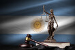 Argentina flag with statue of lady justice, constitution and judge hammer on black drapery. Concept of judgement and punishment
