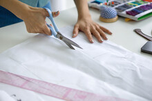 Closeup Dressmaker Hand Use Scissors To Cut Sketch Paper Pattern.
