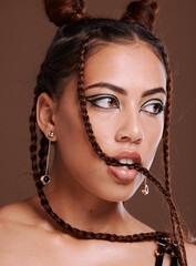 Wall Mural - Makeup, hair and woman biting braid with edgy hairstyle and beauty on a brown studio background. Trendy, cosmetics and cosmetic haircare with braided hair style and cool eyeliner on a studio backdrop