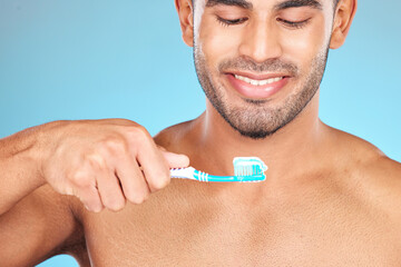 Poster - Toothbrush, toothpaste and man happy brushing teeth for dental care, morning hygiene and cleaning in studio. Smile, tooth whitening and mouth healthcare or oral care happiness in blue background