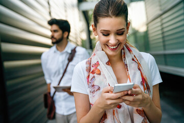 Wall Mural - Outdoors portrait of beautiful young business, student woman laughing and using cell phone