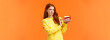 Disgusted and displeased, picky redhead girl look after body shape, dont eat sweets, holding piece tasty cake and refusing eat, showing stop sign, grimace at camera with aversion, orange background