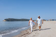 coppia di anziani coniugi si abbraccia affettuosamente mentre cammina lungo la battigia di una spiaggia 