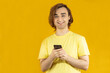 © TSViPhoto - Young man Prep Student with long hair. 20s guy with smartphone on a yellow background